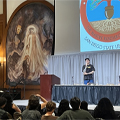 man stands at podium speaking in front of audience
