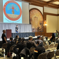 man stands at podium speaking in front of audience