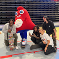 group of people pose with skateboard and Olympics mascot
