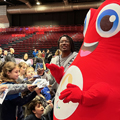 man and Olympics mascot greet school children